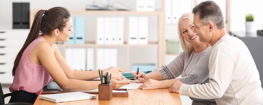 A paralegal works with two clients in a law office, reviewing documents.