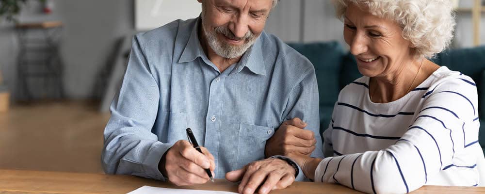 Two people look over legal paperwork together and prepare to sign the documents.